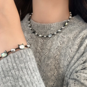 Elegant cat motif pearl necklace and bracelet set shown on model over a gray sweater