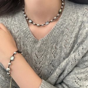 Detailed view of pearl necklace and bracelet set with black cat shell charm on model