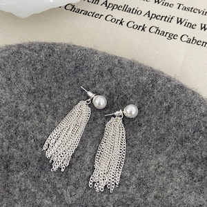 Close-up of silver waterfall tassel earrings with white pearls on a grey textured background