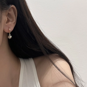 Close-up of elegant gold hollow cube earrings worn by a model in a minimalist style
