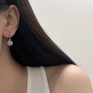 Close-up of elegant silver drop earrings with snowflake zircon pendant on a model