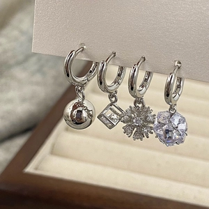 Detailed view of silver hoop earrings set with snowflake and zircon stone charms