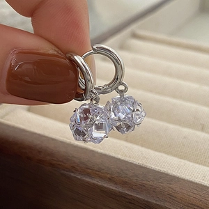 Detailed view of silver hoop earrings with shimmering geometric zircon drops held by hand
