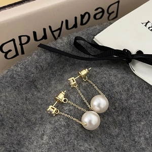 Detailed macro of gold tassel earrings with square crystal and large white round pearl