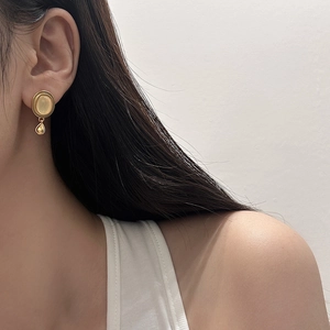 Goldene Ohrstecker mit gelbem Stein und Tropfenanhänger an einem weiblichen Model