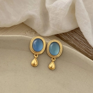 Nahaufnahme der Vintage-Ohrringe mit blauem Katzenaugenstein und Goldtropfen