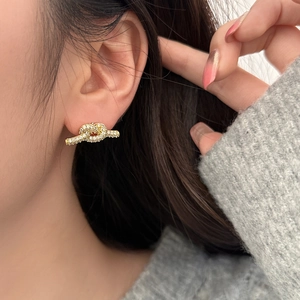 Elegante goldene Knotenohrringe mit Mikro-Pavé-Kristallen am Model getragen