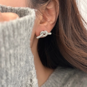 Detail von silbernen Knoten-Ohrsteckern mit Zirkonia-Steinen an einem Model