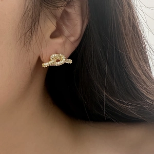Nahaufnahme eines goldenen Knotenohrrings mit Zirkonia-Steinen an einem Model