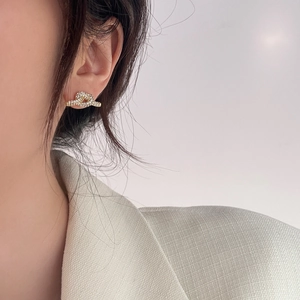 Nahaufnahme eleganter goldener Knotenohrringe mit Mikro-Pavé-Kristallen an einem Model