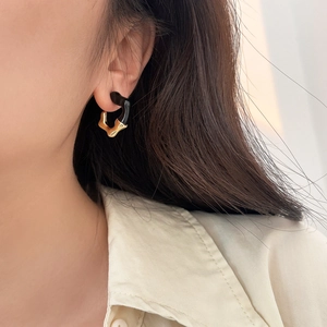 Detail of irregular black enamel and gold fluid ear cuff worn on model's ear