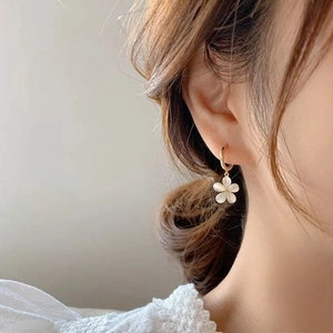 Detail of floral earring with opal stone and gold hook on model, soft lighting view