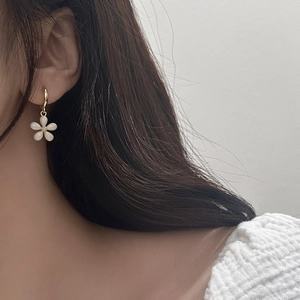 Close-up of elegant flower earrings with pearlescent white petals on gold hoops
