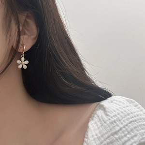Side view of elegant white flower earrings with gold hoop on model showing refined details