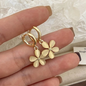 Detail of flower earrings featuring opal-like petals and elegant gold metal finish
