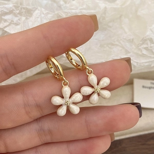 Detailed close-up of cat eye stone flower earrings with gold hoops and pearly finish