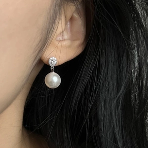Elegant white pearl drop earrings with sparkling micro-pave crystals on a female model