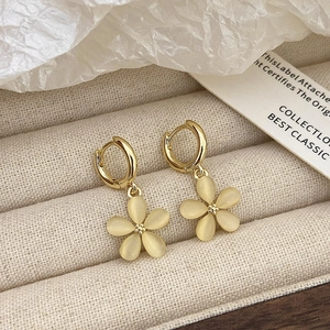Detail of flower dangle earrings with cat eye stone petals on a beige velvet tray