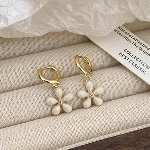 Detail van witte opaal bloem oorbellen op een beige fluwelen sieradendisplay