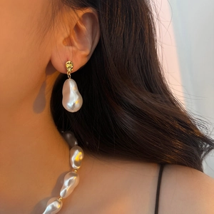 Detailed view of baroque pearl necklace and earrings set with elegant golden accents