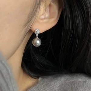 Close-up of dangling pearl earrings with micro-set zircon accents on a model's ear