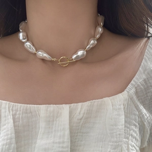 Detailed view of Baroque irregular pearl necklace with gold OT buckle on model neck