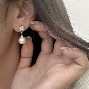Detail of elegant pearl drop earring with micro-pave crystals on female model