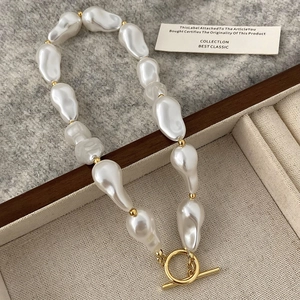 Detailed shot of Baroque irregular pearl necklace featuring a golden OT toggle clasp on felt