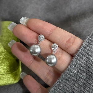 Detailed view of silver hoop earrings with micro-pave crystals and large grey pearls