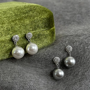 Macro shot of elegant pearl drop earrings with sparkling pavé cubic zirconia studs