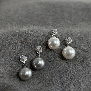 Close-up of white and dark grey pearl earrings with micro-pave cubic zirconia settings