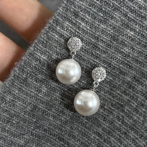 Close-up of pearl drop earrings with micro-pave cubic zirconia on grey knit fabric