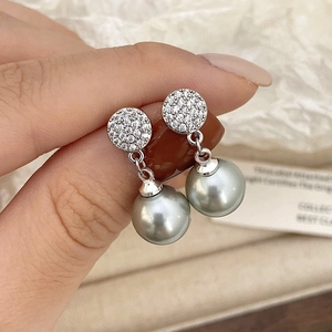 Close-up of silver drop earrings with pavé crystals and elegant grey pearl pendants