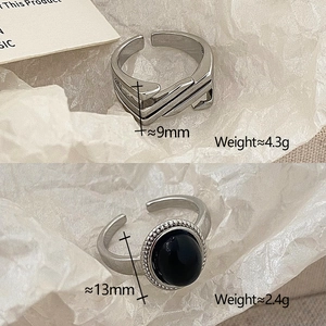 Detail of adjustable geometric silver rings and oval black stone band on paper
