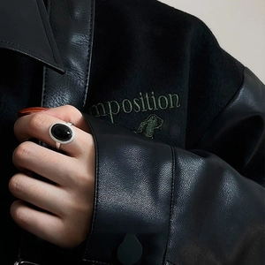 Close-up of a silver ring with an oval black stone and twisted rope texture on a model