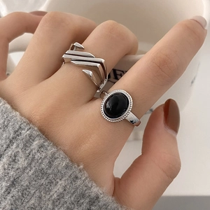 Close-up of hip-hop silver geometric ring and black oval gemstone ring on model finger