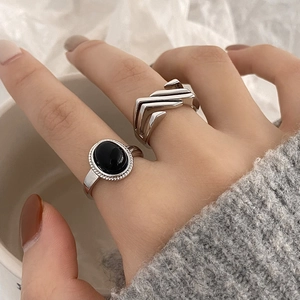 Detail of silver rings with black oval stone and geometric layering on hand