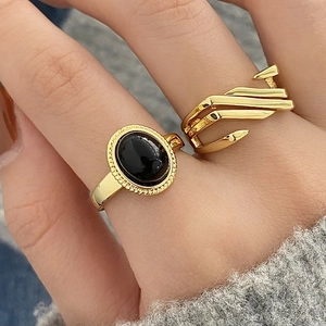 Detail of vintage gold ring with black stone and modern geometric flowing band
