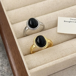 Macro detail of vintage gold and silver rings with oval black gemstones on beige velvet