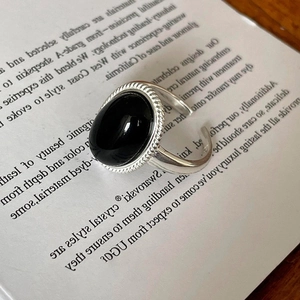 Close-up of vintage silver open ring with a large oval black gemstone on book pages