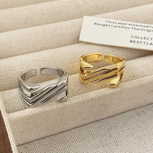 Macro shot of geometric layered adjustable rings in polished gold and silver finishes