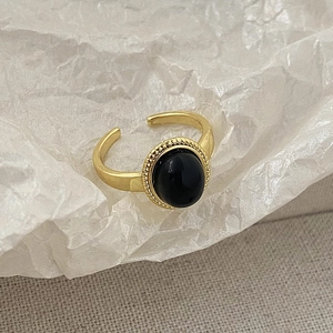 Detail of adjustable gold ring featuring an oval black gemstone and beaded vintage texture