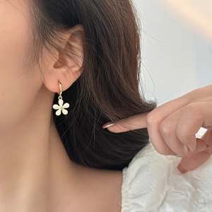 Elegant floral drop earrings with white petals and gold hoops worn by a model
