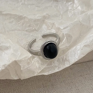 Detailed close-up of retro silver ring with oval black stone and beaded edge design