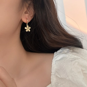 Elegant matte gold flower charm earrings on model for a sophisticated French style look