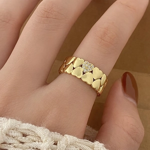 Macro shot of gold heart ring with pavé cubic zirconia worn against a cozy knit sweater