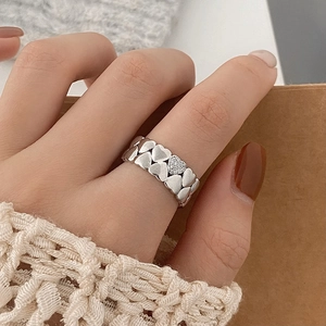 Close-up of heart-shaped silver ring with zircon stones worn by a model