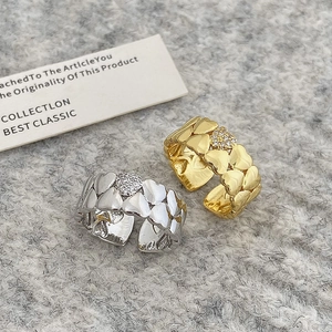 Macro detail of gold and silver heart-shaped adjustable rings with sparkling zircons