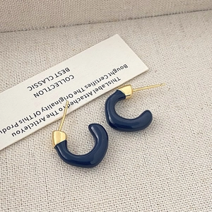Dettaglio dei orecchini a forma di C in smalto blu scuro con finitura in metallo dorato