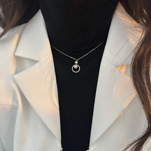 Detail der eleganten Perlenkette mit Zirkonring, getragen über schwarzem Rollkragenpullover